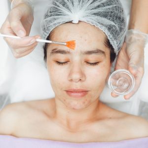 A cosmetologist does facial care and apply a face mask. cleansing a heavily soiled face.